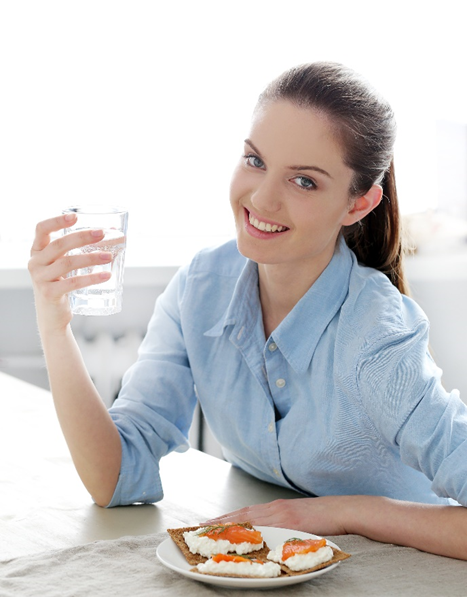 a woman holding a glass of water and a plate of food
